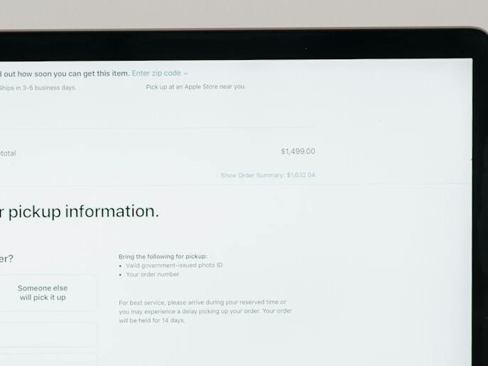 Modern laptop displaying a checkout form against a minimalist beige backdrop.
